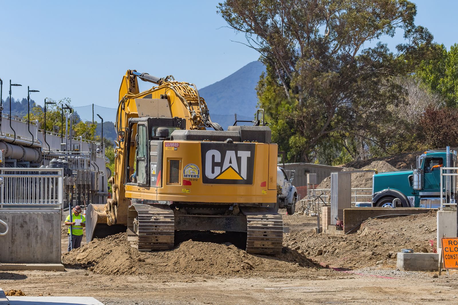 A tracked excavator moving earth on an open construction site.